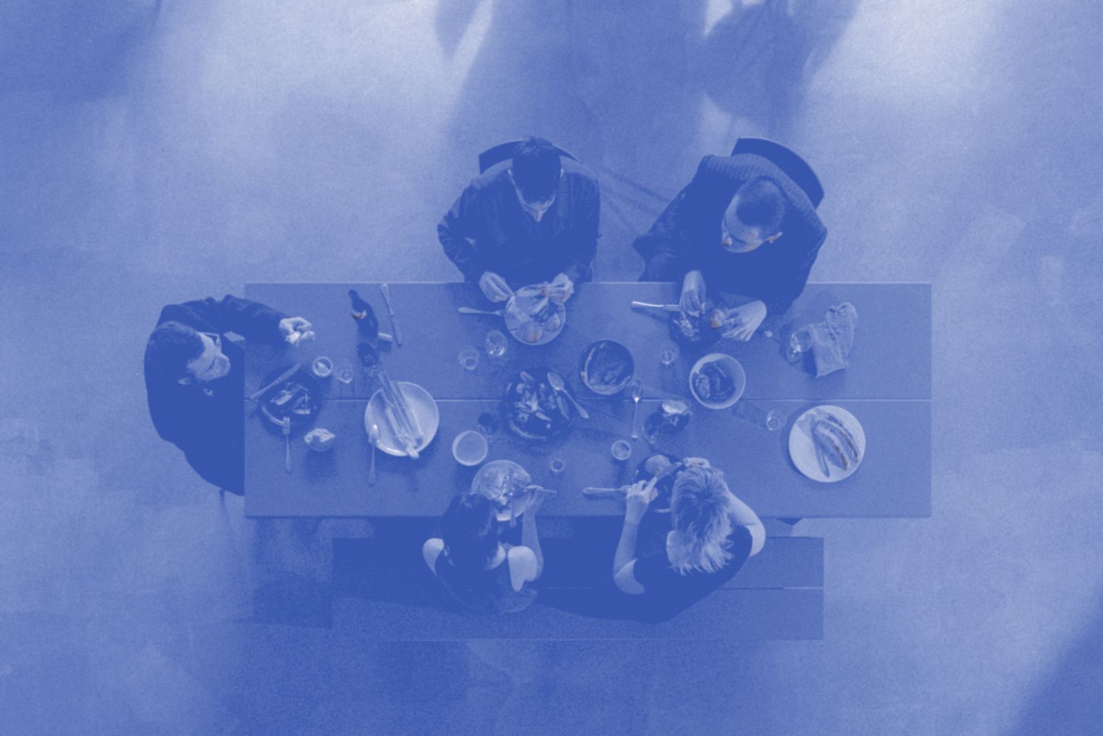 A long table of friends sharing plates, seen from above